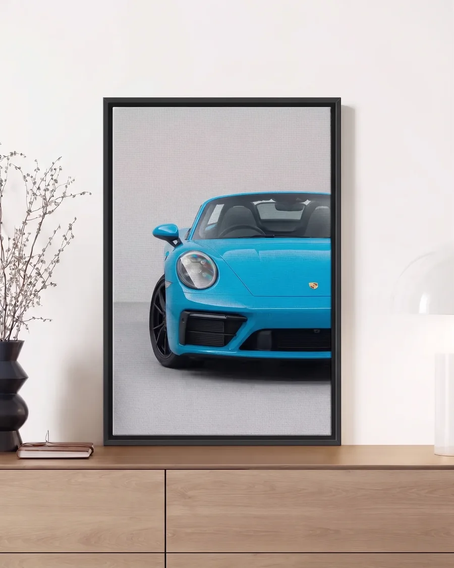 A blue Porsche 911 on canvas in a slim black floating frame, leaning on a sideboard