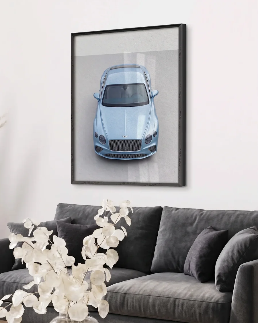 A framed print of a pale blue Bentley Continental GT from above, in a black wooden frame on a living room wall